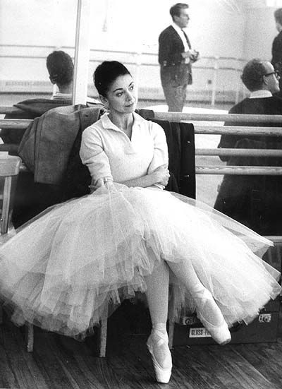 black and white photograph of a woman sitting on a chair in front of other people