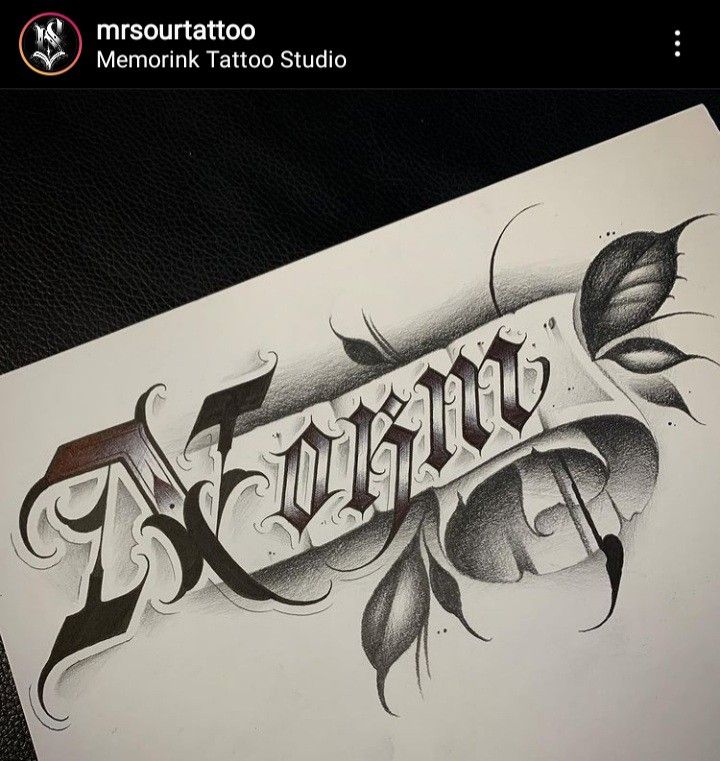 the word tattoo is written in black and white ink on a piece of paper with leaves