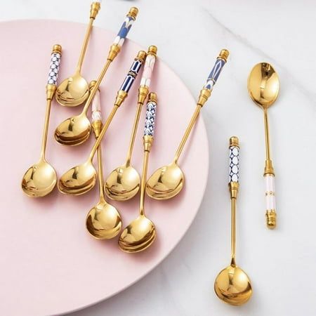 gold spoons and forks on a pink plate next to some other utensils