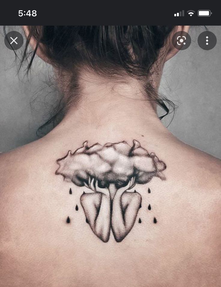 the back of a woman's neck with a cloud and rain tattoo on it