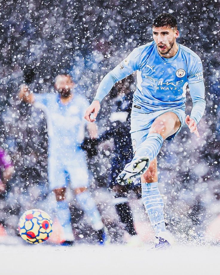 a man kicking a soccer ball on top of a snow covered field in the rain