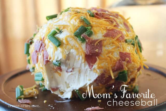 a cheese ball covered in bacon, green onions and other toppings on a plate