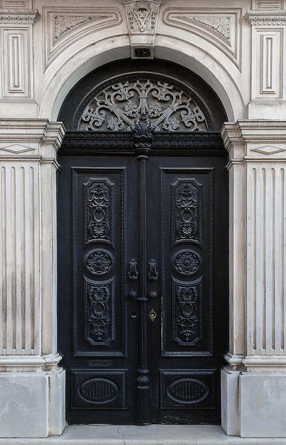 two black doors with ornate carvings on the front and side of an old church building