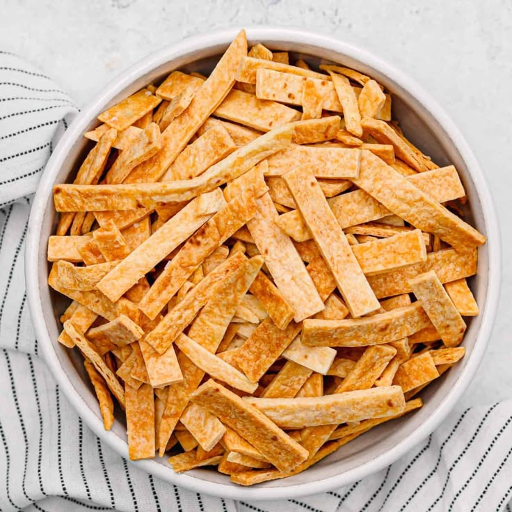 a white bowl filled with cheesy crackers on top of a striped towel