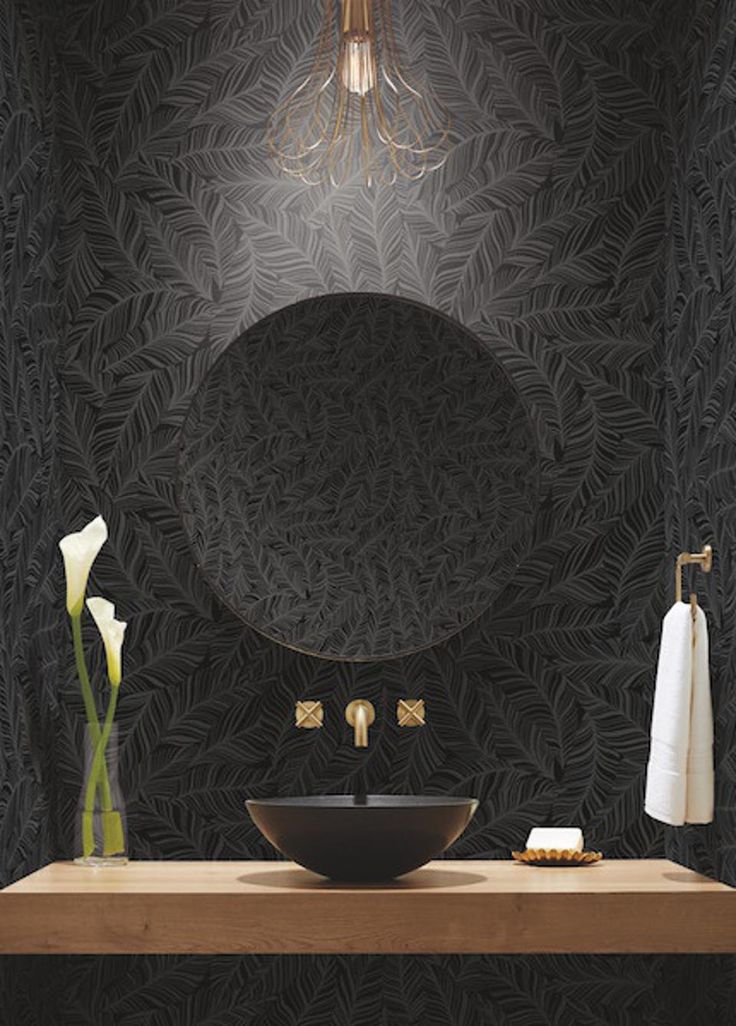 a bathroom with a sink, mirror and towel rack in front of black wallpaper