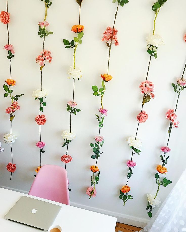 a laptop computer sitting on top of a white table next to a wall covered in flowers