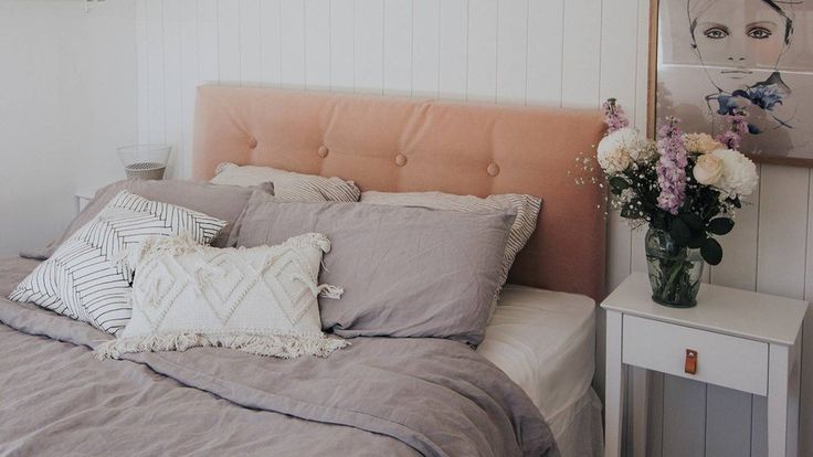 a bedroom with a bed, nightstand and flowers in vases on the side table