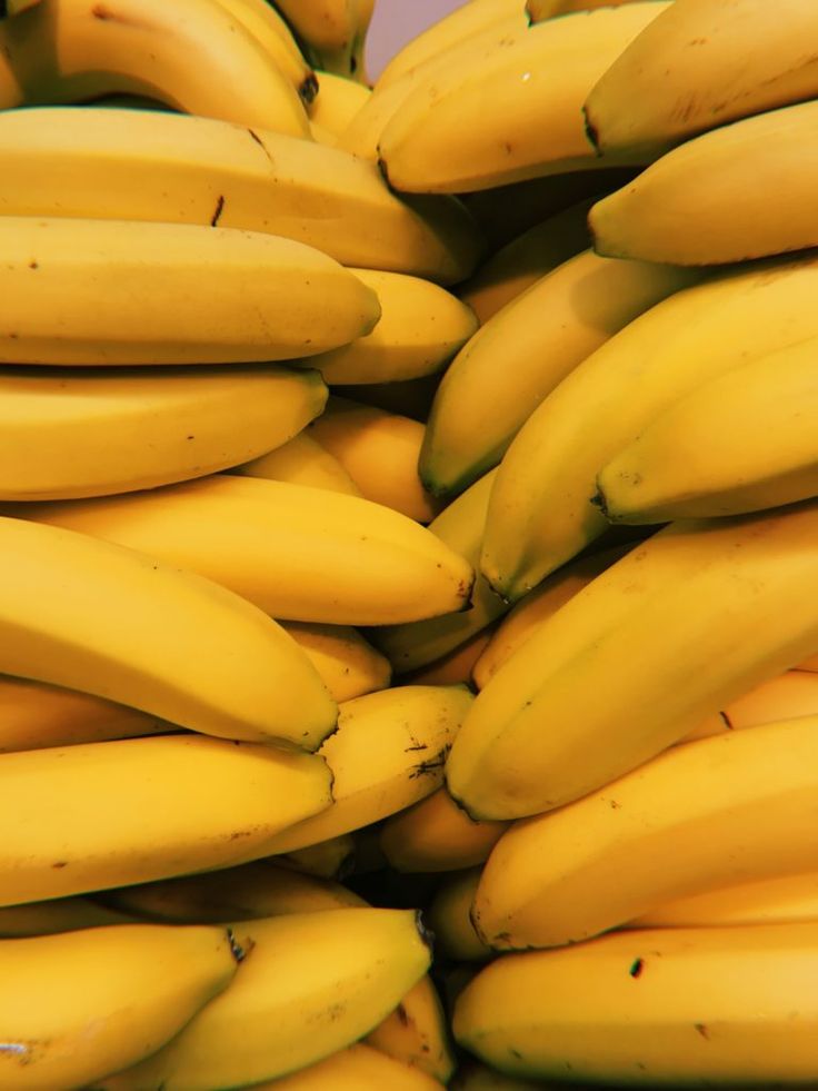 bunches of ripe bananas are stacked on top of each other in a large pile