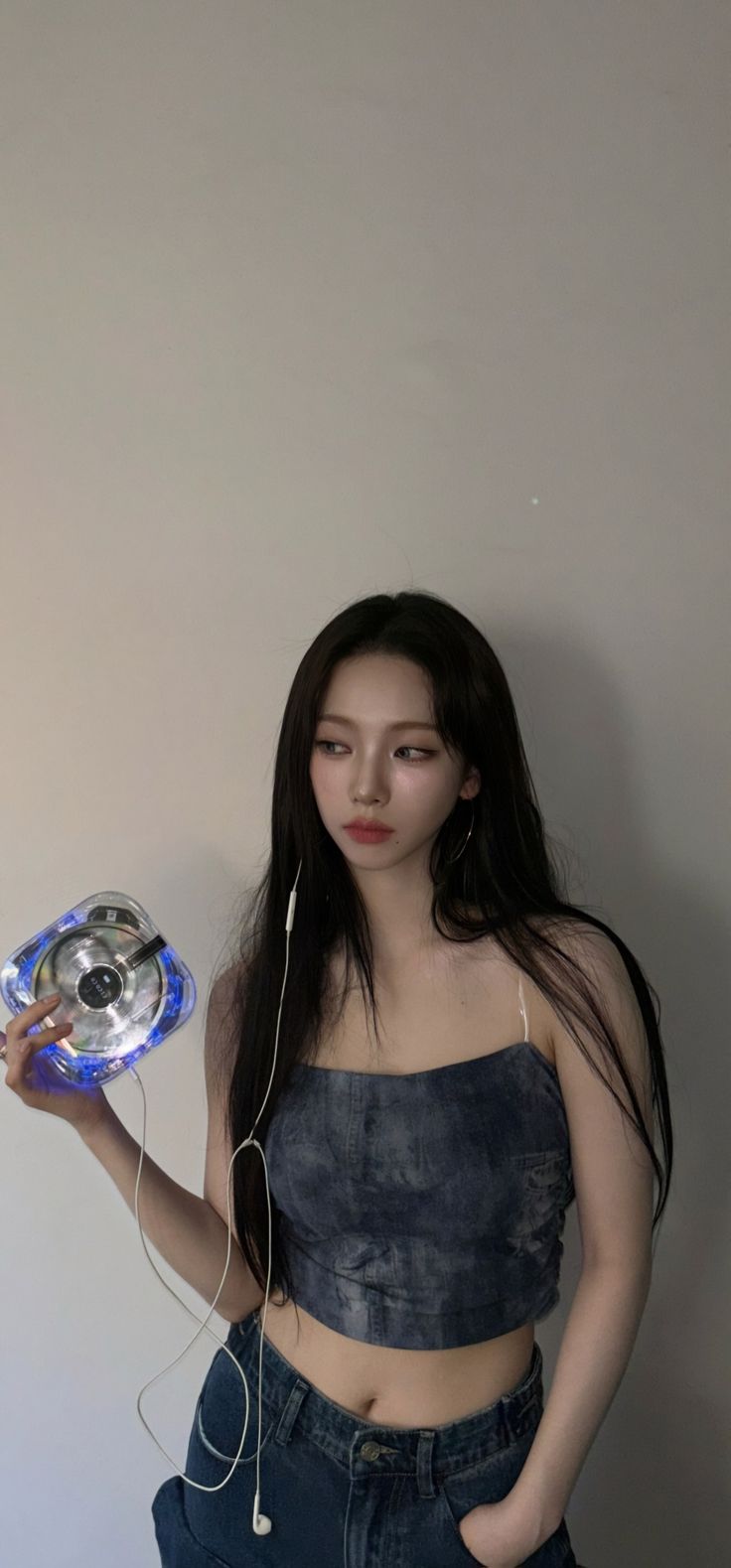 a woman with headphones is holding a blue object in her hand and looking at the camera