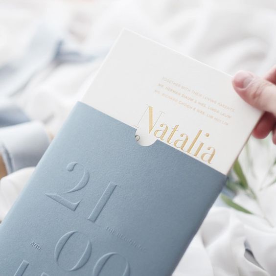 a person holding up a blue book with gold lettering