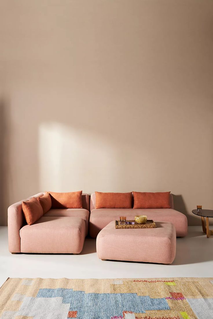 a pink couch sitting on top of a rug next to a table