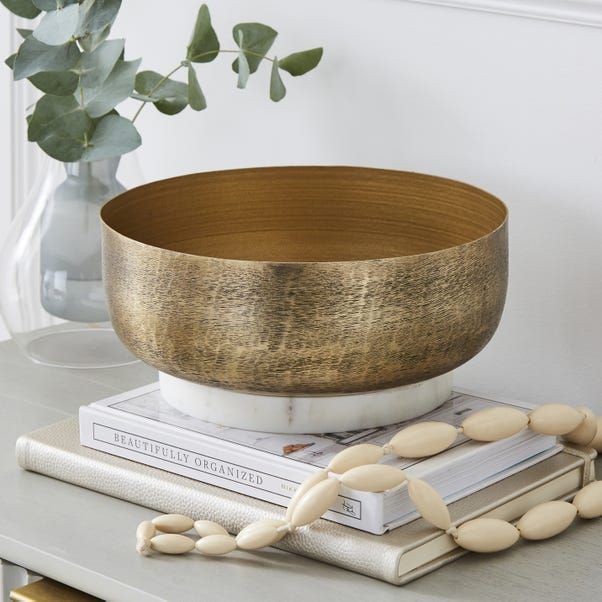 a wooden bowl sitting on top of a table next to some books and a plant