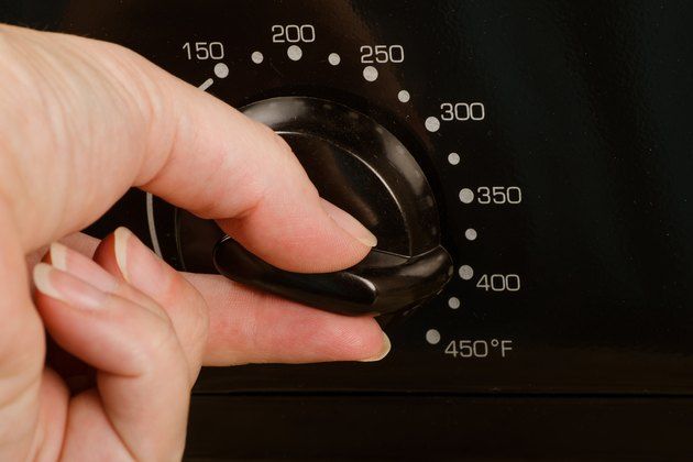 a person pressing the knob on an oven with their thumb in it's hand