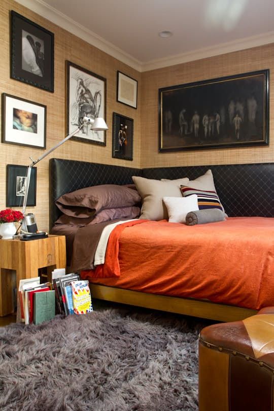 an orange bed in a bedroom with pictures on the wall and carpeted flooring