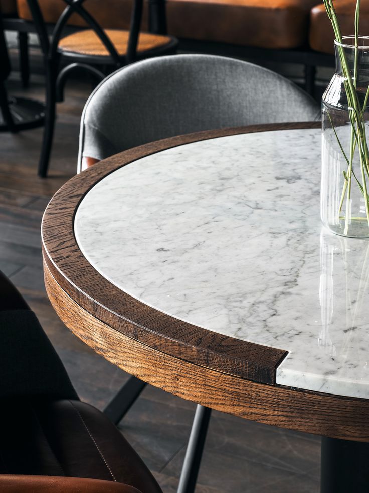 a vase with some flowers sitting on top of a marble topped table in a restaurant