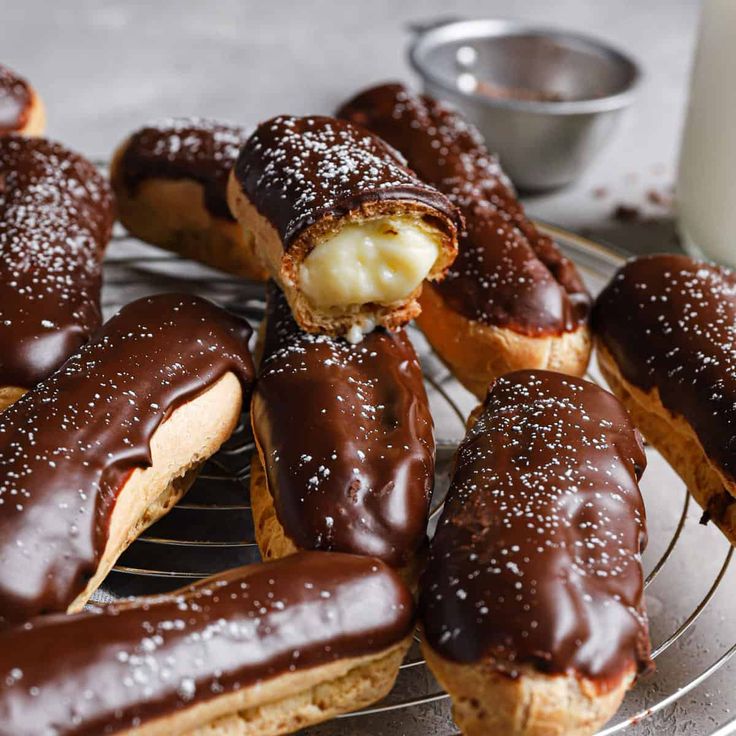 chocolate covered doughnuts on a cooling rack next to a glass of milk