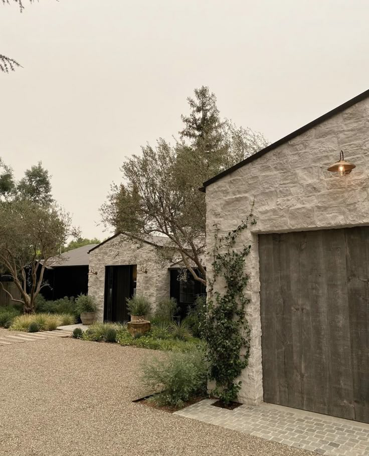 an old stone building with a garage and trees in the backgroung area