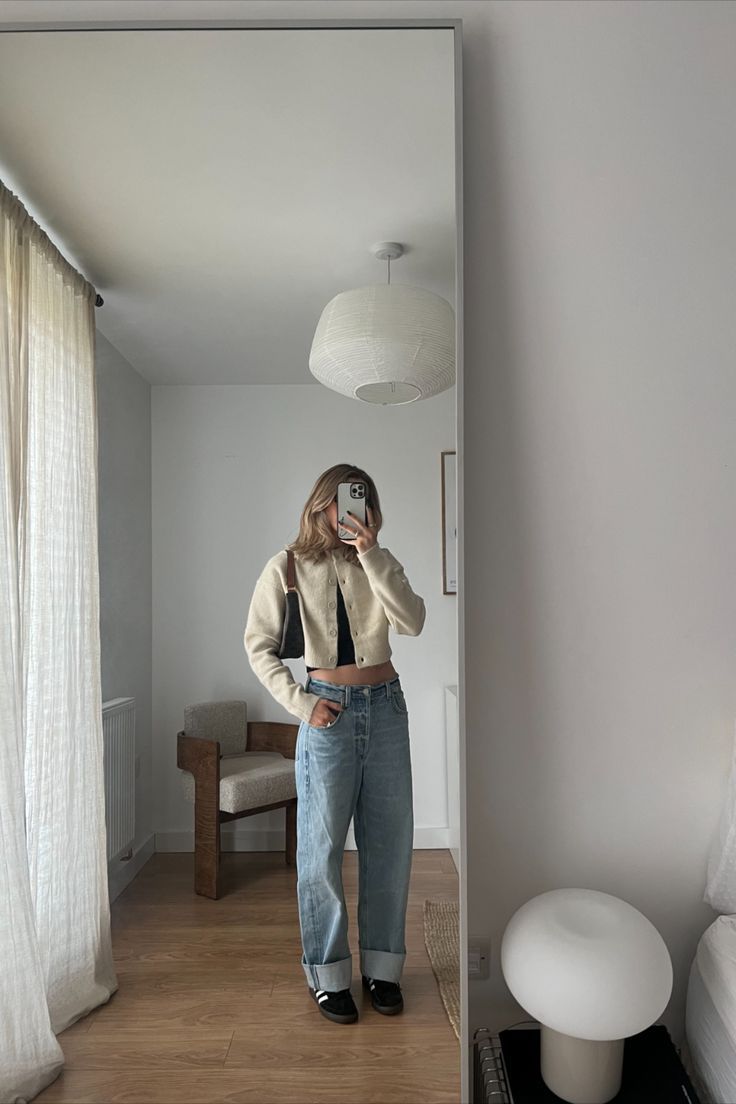 a woman taking a selfie in the mirror with her cell phone while standing next to a bed