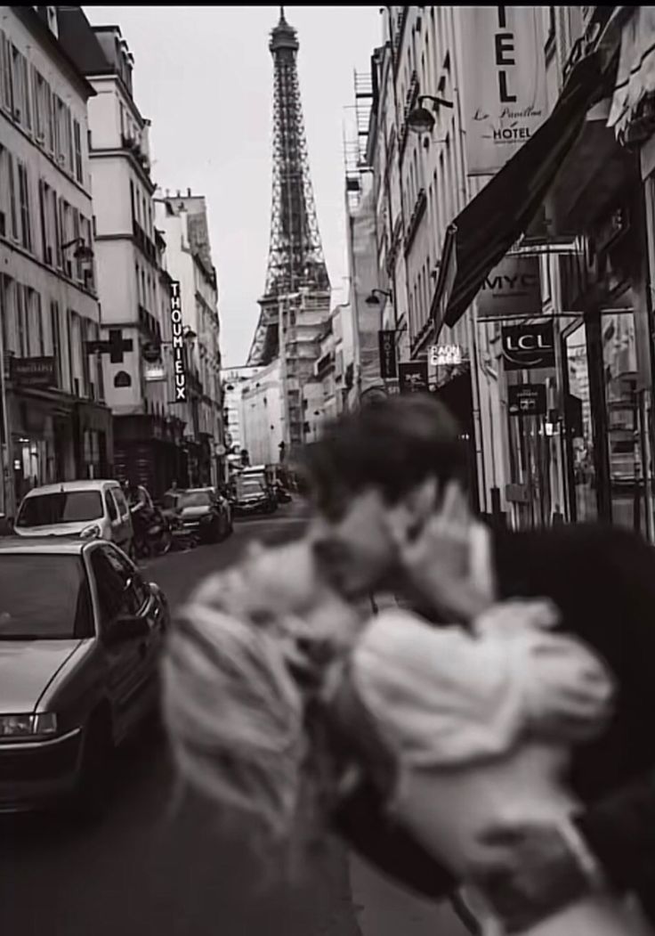 black and white photograph of man talking on cell phone in front of the eiffel tower