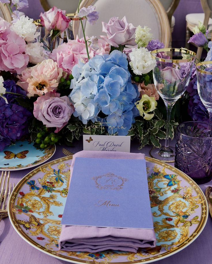 the table is set with purple and blue flowers