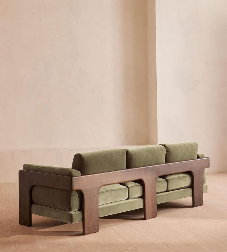 a green couch sitting on top of a hard wood floor next to a white wall