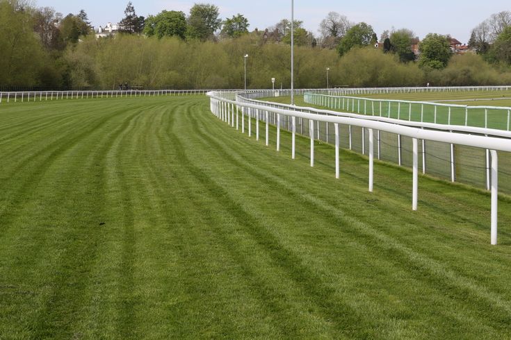 a horse race track with white fences and green grass