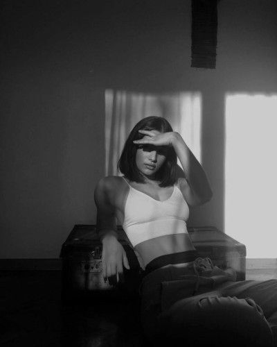 a black and white photo of a woman sitting in a chair with her hand on her head