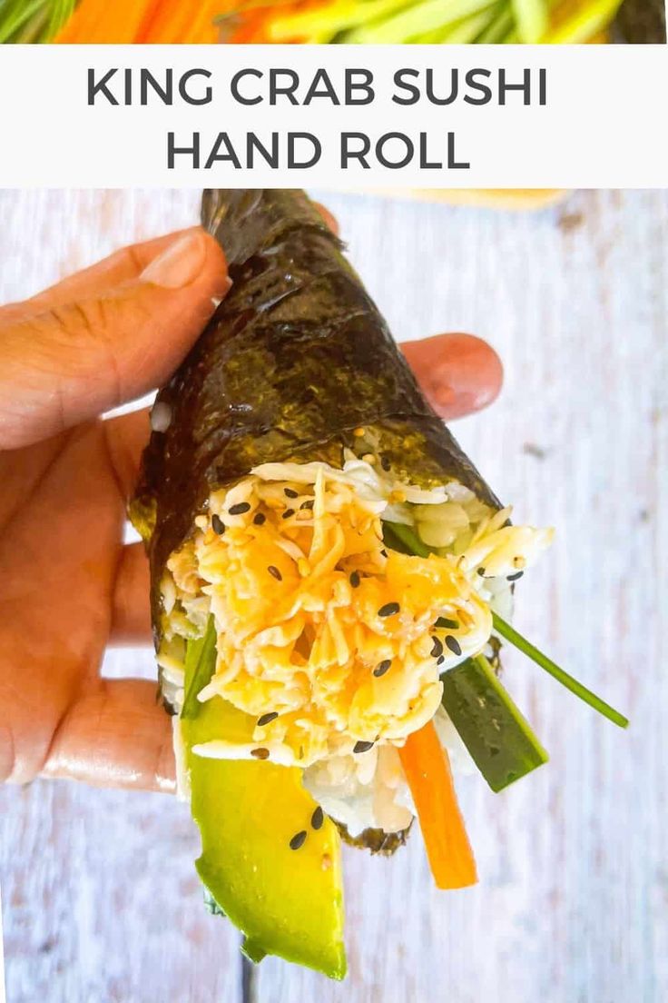 a hand holding a vegetable sushi roll with text overlay that reads king crab sushi hand roll