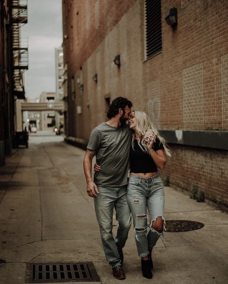 a man and woman are walking down the street in front of a brick building together