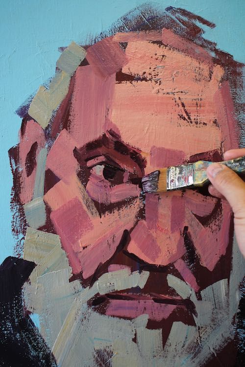 someone is painting a man's face on the wall with red and brown paint