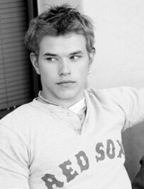 black and white photograph of a young man wearing a sweater with the word red sox on it