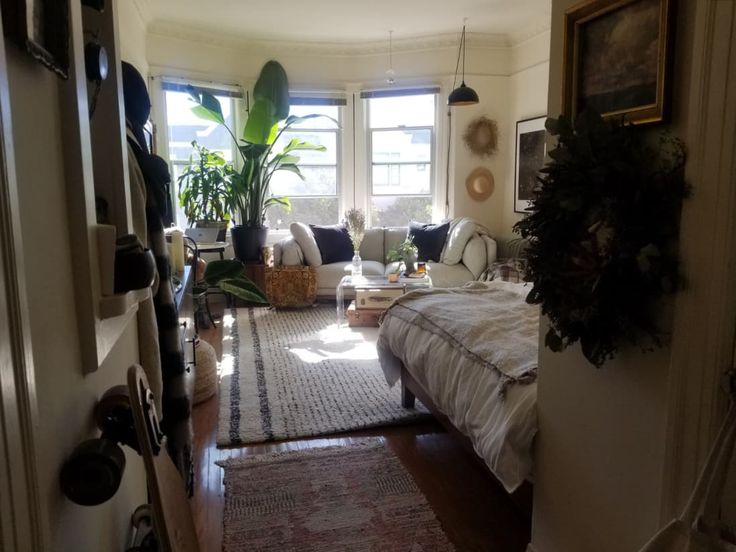 a living room filled with lots of furniture and plants on top of the windowsill