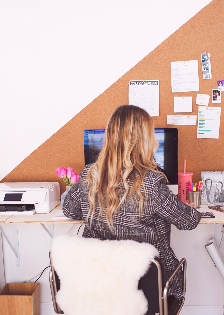 a woman sitting at a desk in front of a computer monitor and keyboard on top of a white chair