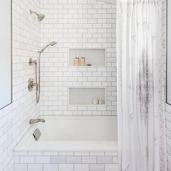 a white tiled bathroom with shower and bathtub