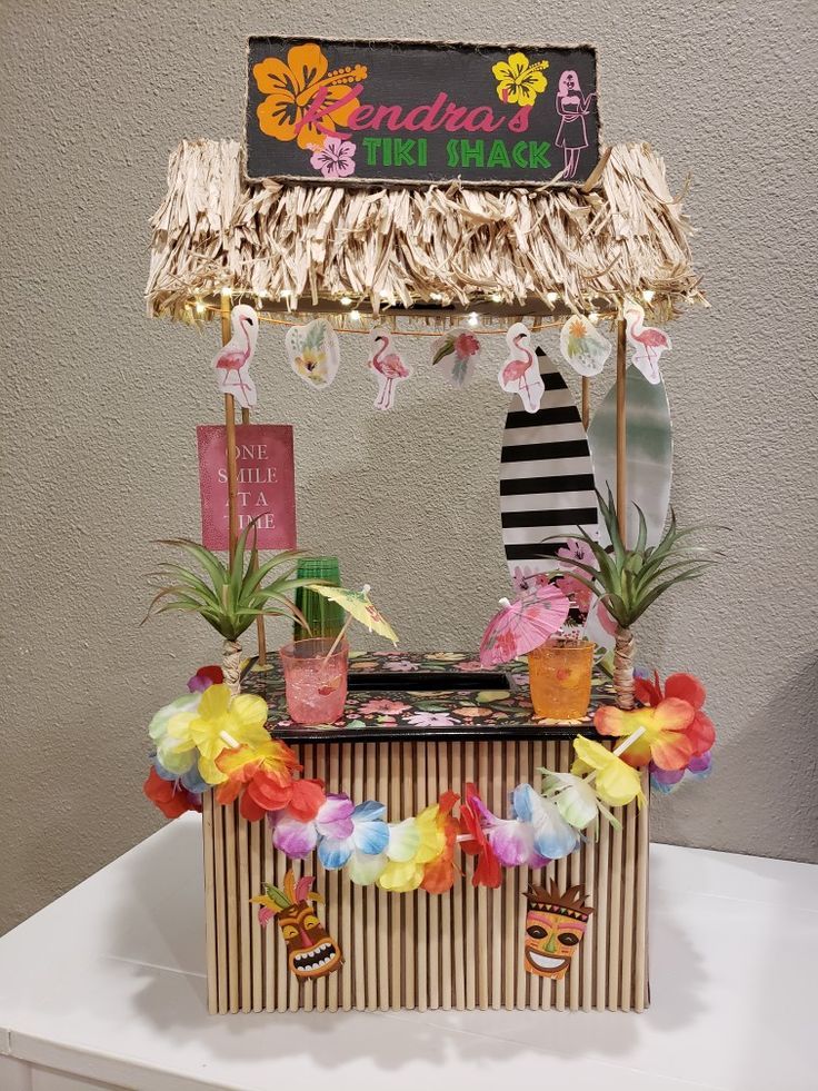 an ice cream stand decorated with flowers and tiki hut decorations for a hawaiian themed birthday party