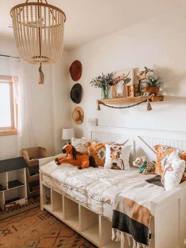 a white bed sitting in a bedroom next to a wooden shelf filled with stuffed animals