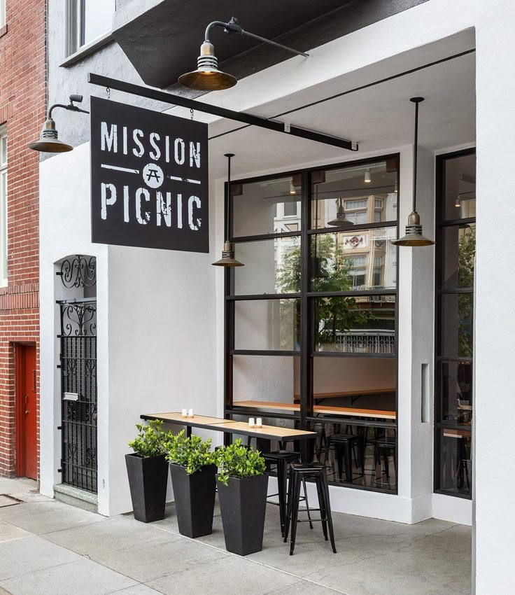 the entrance to mission picnic with two planters on the sidewalk and tables in front