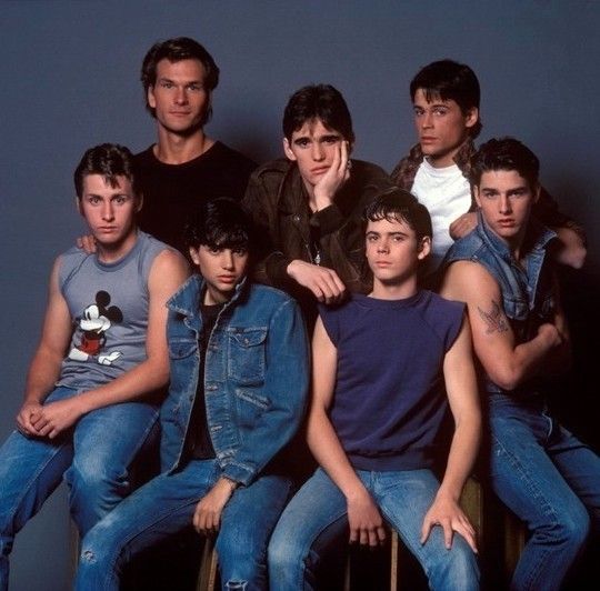 a group of young men sitting next to each other in front of a blue wall