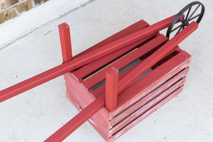 a red wooden crate with wheels on it