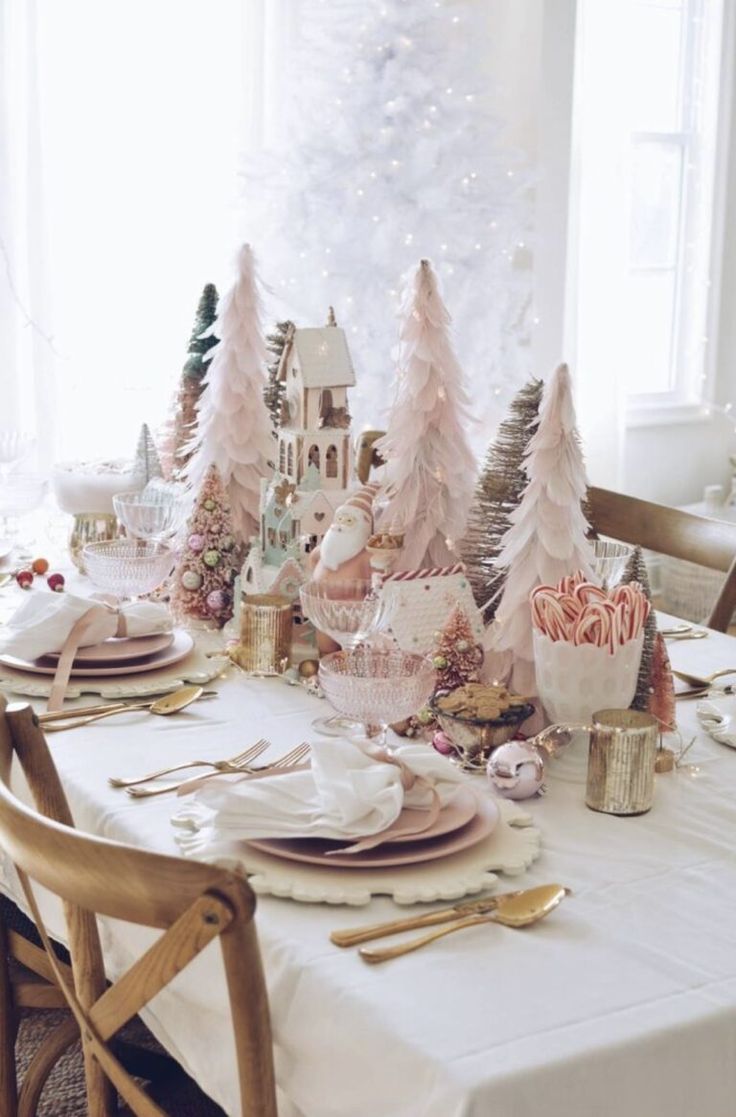 a dining room table set for christmas with pink and white trees in the background,