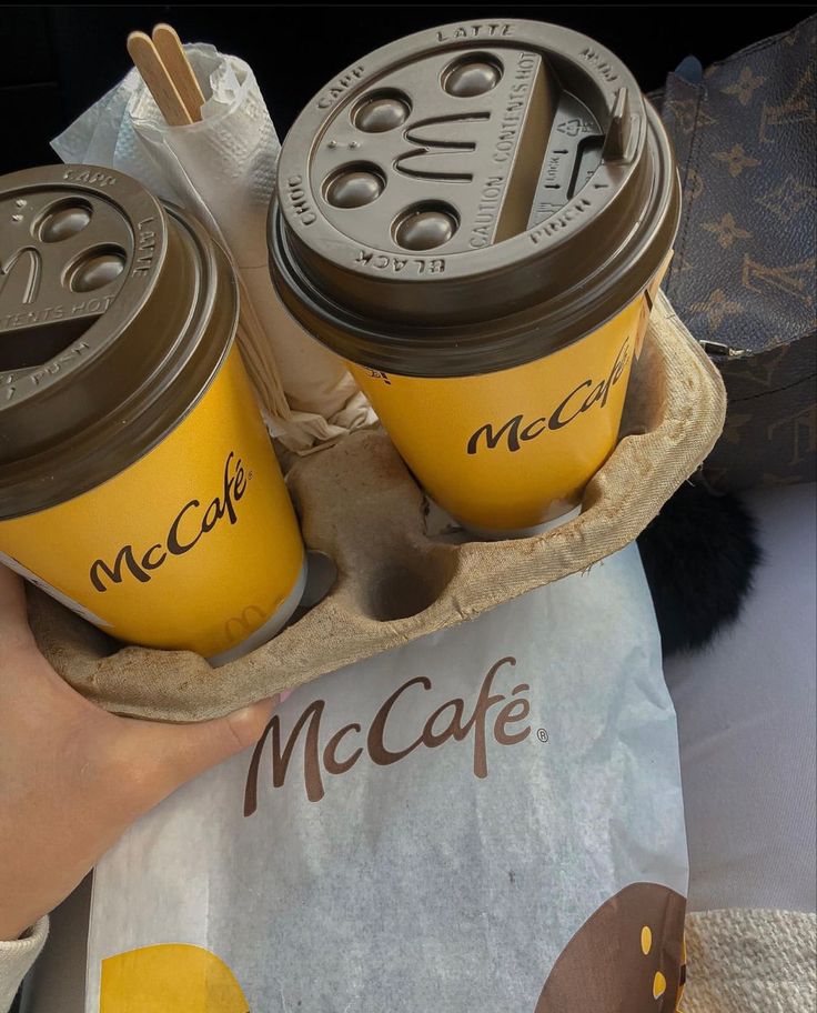 two coffee cups sitting on top of each other in a paper tray with the lids open