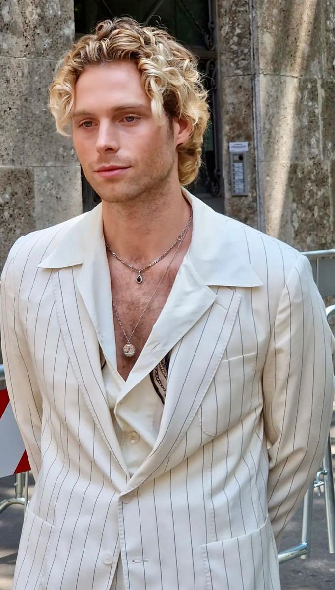 a man in a white suit standing next to a building