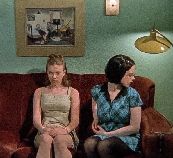 two women sitting on a couch talking to each other