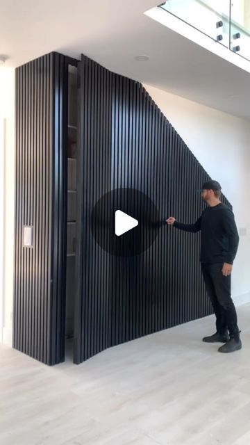 a man standing in front of a large black piece of art that is on display