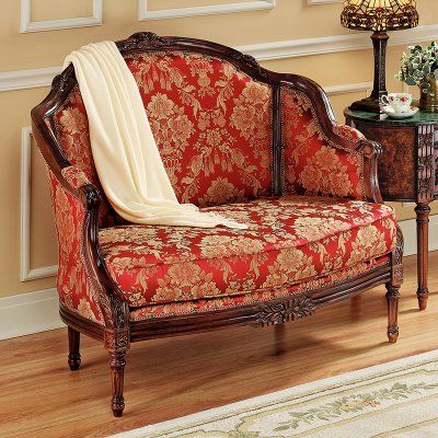 a red and gold couch sitting on top of a wooden floor next to a table