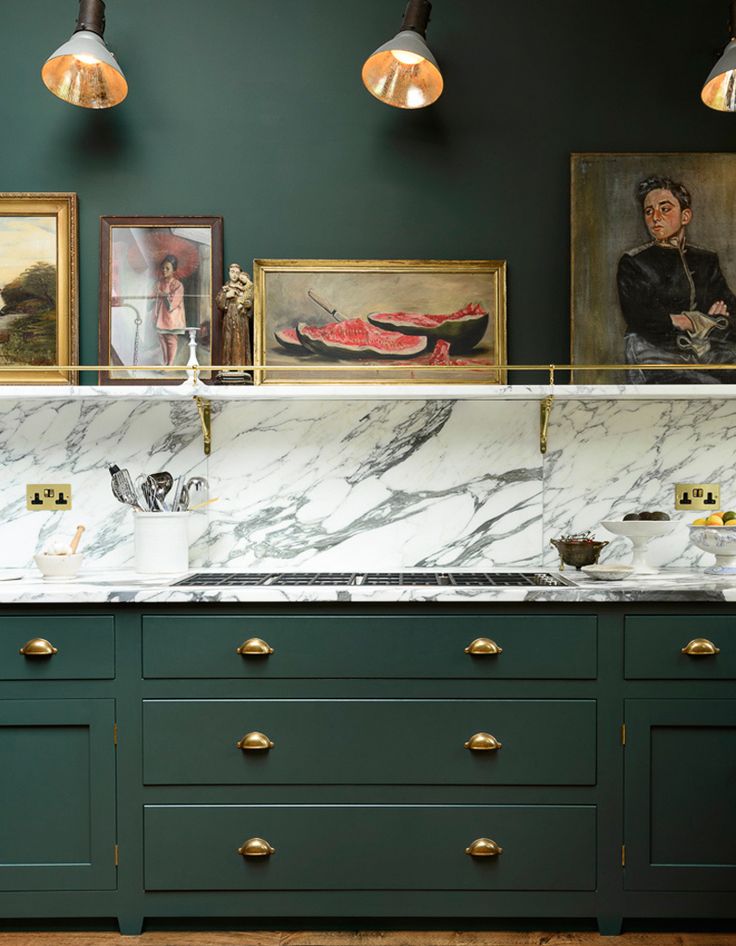 a kitchen with green cabinets and marble counter tops, gold pulls on the handles and brass knobs