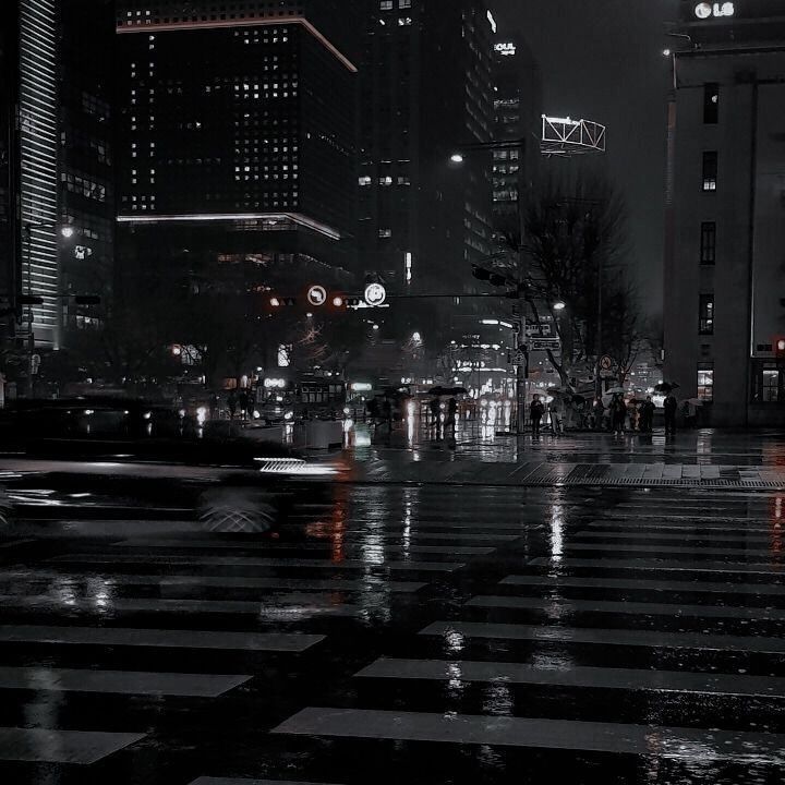 an empty city street at night with rain on the ground and buildings in the background