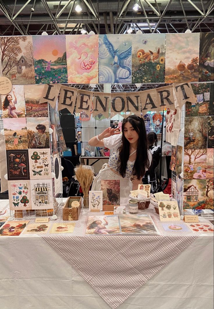 a woman standing in front of a table with pictures on it