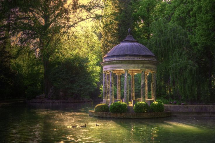 a gazebo sitting on top of a lake surrounded by trees