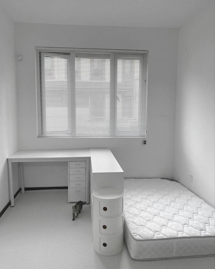 an empty room with a bed, desk and drawers on the bottom floor is shown in black and white